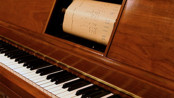 Player piano with a physical piano roll inside.